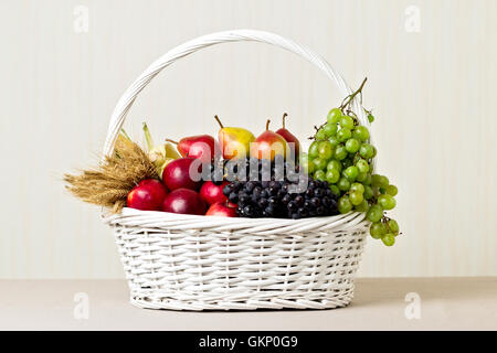 Panier blanc avec raisins, pommes et poires. Banque D'Images