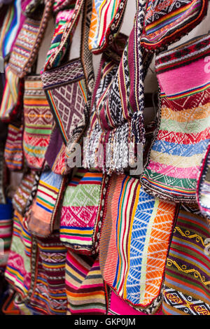 Près d'un mur recouvert de sacs fait main dans de belles couleurs péruviennes à vendre au marché de Pisac au Pérou. Banque D'Images