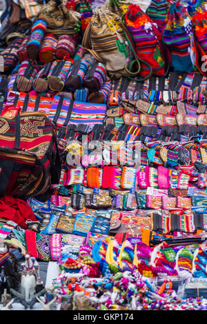 Près d'un mur recouvert de sacs fait main dans de belles couleurs péruviennes à vendre au marché de Pisac au Pérou. Banque D'Images