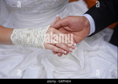 Groom tient sa main de la mariée avec anneau de mariage Banque D'Images