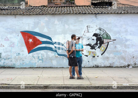 Deux hommes debout en face d'un révolutionnaire d'une fresque sur un mur dans la vieille ville de La Havane (La Habana Vieja), Cuba Banque D'Images