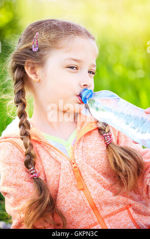 Petite fille mignonne sur la nature des boissons de l'eau d'une bouteille en plastique Banque D'Images