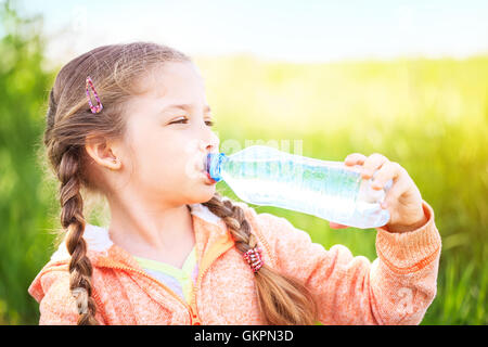 Petite fille mignonne sur la nature des boissons de l'eau d'une bouteille en plastique Banque D'Images