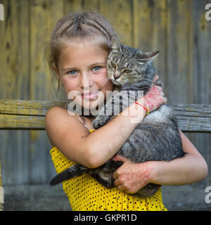 Funny little girl holding un chat dans ses bras. Banque D'Images