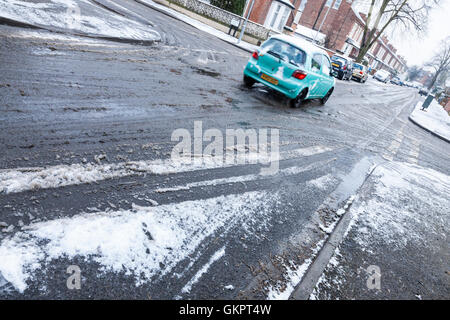 Route mouillée en hiver. Voiture roulant le long d'une rue résidentielle d'hiver avec de la neige fondante après une légère chute de neige, Lancashire, England, UK Banque D'Images