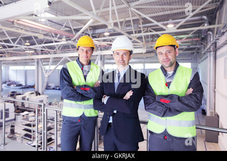 Équipe de manager et deux travailleurs en usine CNC Banque D'Images