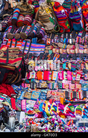 Près d'un mur recouvert de sacs fait main dans de belles couleurs péruviennes à vendre au marché de Pisac au Pérou. Banque D'Images