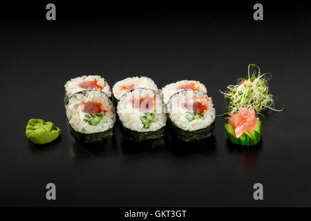 Rouleaux de sushi japonais frais avec du thon et des concombres décorée de salade d'algues et wasabi Banque D'Images