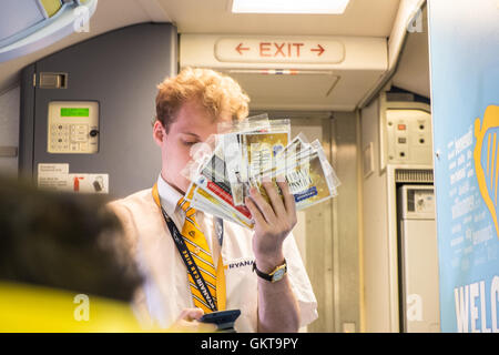 L'intendance de bord d'essayer de vendre les cartes à gratter à bord en cabine d'un vol Ryanair. Banque D'Images