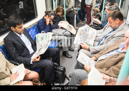 Londres,transport,les habitants de lire les journaux et livres à l'intérieur de London Underground tube train.Sur le point d'arriver à la station de métro Waterloo, London.Angleterre Banque D'Images