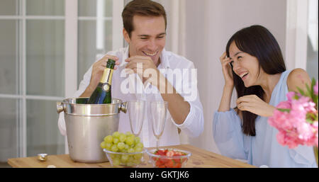 Jeune couple choqué lors de l'ouverture du champagne Banque D'Images