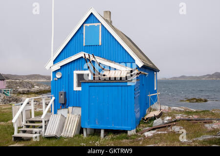 Les Inuits typiques maisons en bois peintes en bleu et avec des traîneaux à l'extérieur. Itilleq, Qeqqata, au Groenland. Banque D'Images