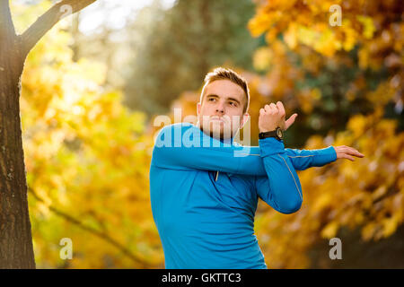 Beau jeune hipster runner stretching à l'extérieur à l'automne natur Banque D'Images