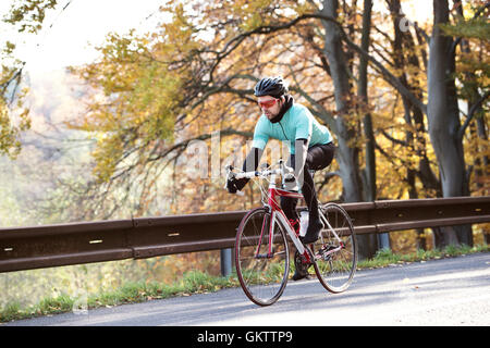 Jeune sportif équitation son vélo à l'extérieur sous le soleil de l'automne natur Banque D'Images