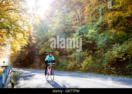 Jeune sportif équitation son vélo à l'extérieur sous le soleil de l'automne natur Banque D'Images