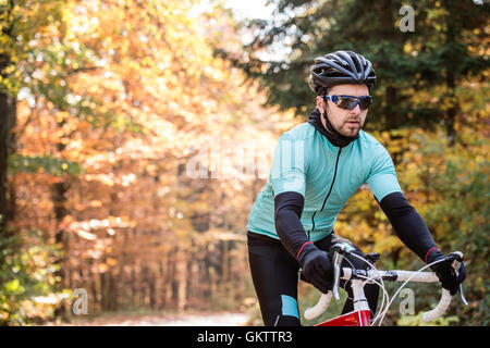 Jeune sportif équitation son vélo à l'extérieur sous le soleil de l'automne natur Banque D'Images