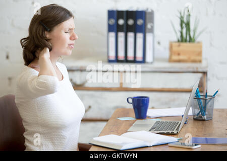 Les jeunes ont souligné businesswoman sitting in front of laptop et tenant son cou avec expression douloureuse. Business Woman feeling Banque D'Images