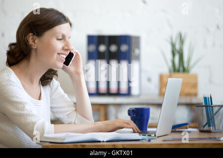 Portrait of young business woman talking on phone in home office dans l'intérieur de l'espace loft. Heureux personne bureau occasionnel Banque D'Images