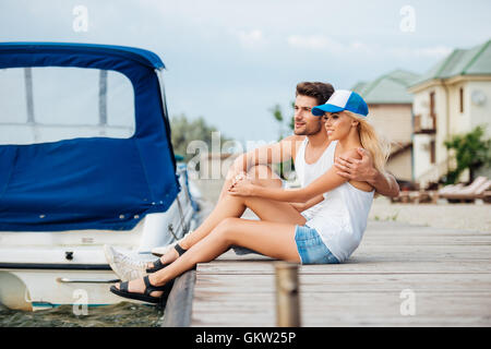 Beau jeune couple hugging et sittung ensemble sur pier Banque D'Images