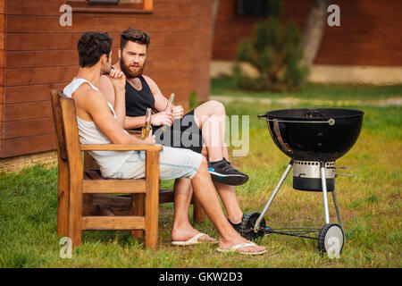 Deux jeunes hommes parlant lors de la préparation du barbecue dans la zone du parc Banque D'Images