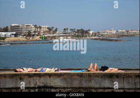 Les femmes de soleil sur mur par Bay le long de la promenade Paphos - Chypre Banque D'Images