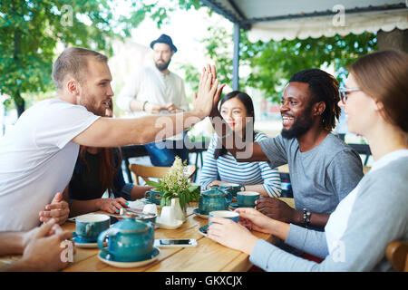 Deux gars interculturel shaking hands parmi leurs amis Banque D'Images