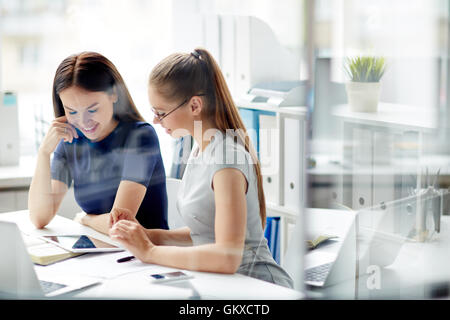 Deux femmes d'heureux l'analyse des données électroniques in office Banque D'Images
