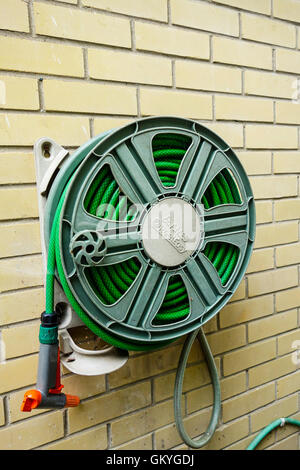 Un jardin Arrosage enroulé reel system sur un mur de la maison en brique Banque D'Images