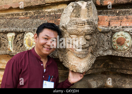 Un homme birman dans un temple de Bagan, Myanmar (Birmanie). L'homme se tient debout devant l'une d'une sculpture en pierre dans un de nos nombreux t Banque D'Images