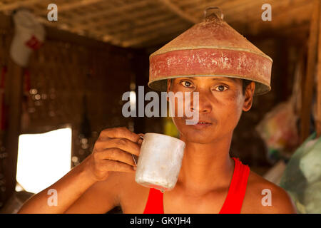 Un homme Birman à Bagan, Myanmar (Birmanie). L'homme est titulaire d'une tasse de thé et porte un chapeau d'étain. Banque D'Images