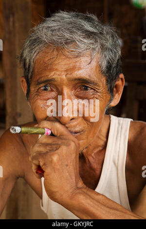 Un homme birman de fumer à sa maison dans Minnathu Village près de Bagan, Myanmar (Birmanie). L'homme fume un cigare roulé à l'échelle locale. Banque D'Images