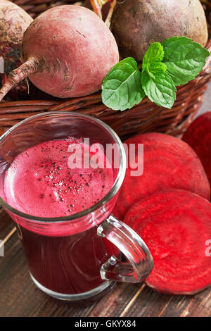 Jus de Betteraves rouges sur fond de bois avec betterave et de feuilles de menthe en panier tressé Banque D'Images