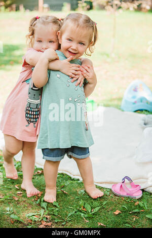 Les deux petites filles de bébé jouant contre l'herbe verte Banque D'Images