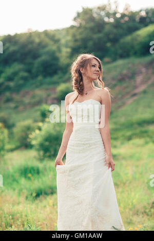 Bride se dresse sur un fond d'herbe et les montagnes. Banque D'Images