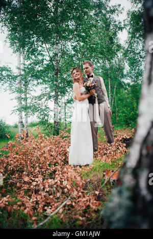 Bride and Groom hugging sur l'arrière-plan de feuilles et des forêts Banque D'Images