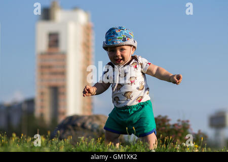 Mignon Bébé Garçon jouant et riant dans le parc. L'été est beaucoup de verdure autour d'une des choses intéressantes pour les miettes. Enfant 1 ans Banque D'Images