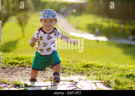 Mignon Bébé Garçon jouant et riant dans le parc. L'été est beaucoup de verdure autour d'une des choses intéressantes pour les miettes. Enfant 1 ans Banque D'Images