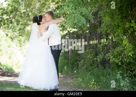 Young Caucasian couple kissing mariage en plein air. Beautiful happy bride embrassant et baisers avec groom sur jour de mariage en été Banque D'Images