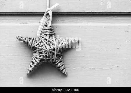 Wicker star accroché sur la paroi en bois blanc, une décoration de Noël. Fond noir et blanc photo Banque D'Images