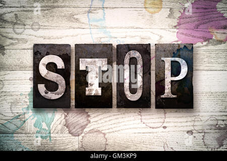 Le mot 'STOP' écrit en vintage metal sale type typographique sur un fond de bois blanchis par l'encre et de taches de peinture. Banque D'Images