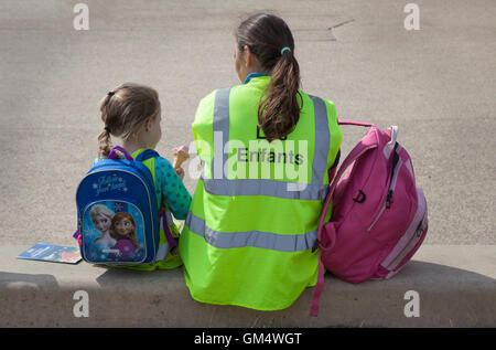 Les enfants accompagnant le port 'Les Enfants' Veste haute visibilité sur la promenade de Blackpool, Lancashire, UK Banque D'Images