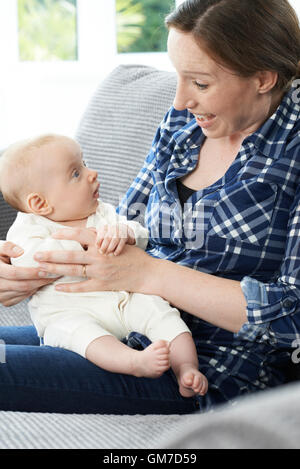 Mère Fille Bébé câlins sur canapé Banque D'Images