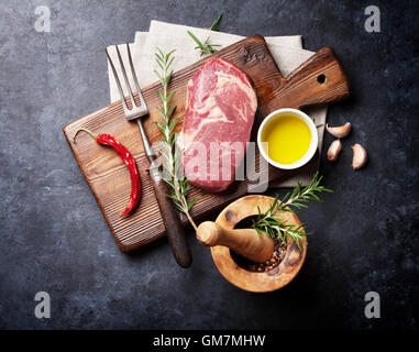 Pavé de boeuf cru et la cuisson des ingrédients. Morceau de viande, d'herbes et d'épices. Vue de dessus plus table en pierre Banque D'Images