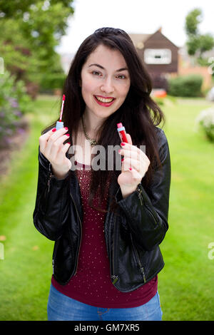 Young woman holding her Lip Gloss Banque D'Images