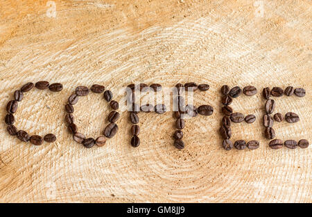 Le mot Coffee énoncés à l'aide de grains de café torréfiés sur un fond de bois naturel. Banque D'Images