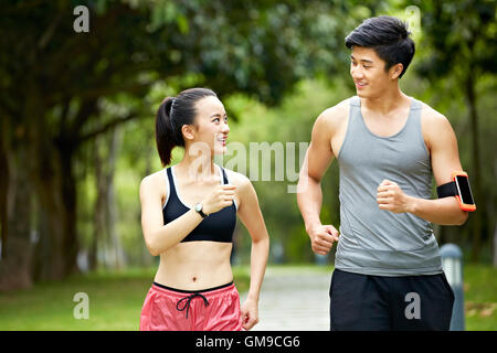 Young Asian man and woman couple running jogging et parler dans un parc de la ville. Banque D'Images