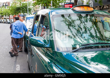 Les chauffeurs de taxi à une station de taxi debout à côté de leur cabine en attente de tarifs, Nottingham, England, UK Banque D'Images