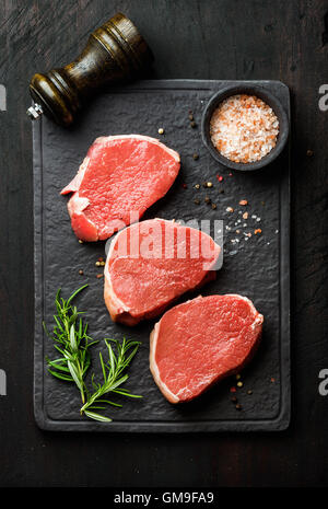 Oeil de Boeuf cru steaks ronds avec des épices et de romarin Banque D'Images