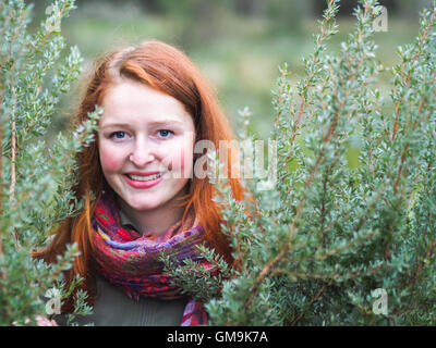 Portrait of smiling redhead dans les buissons Banque D'Images