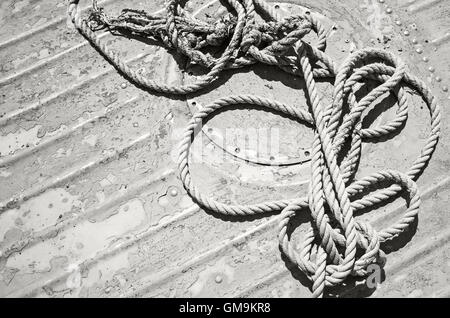 Amarre noués allongé sur grungy pont de bateau, ancien style de photo en noir et blanc Banque D'Images